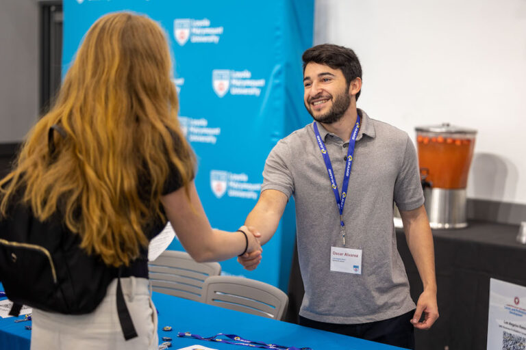 Student shakes hands with Rams representative at LMU Career Fair.